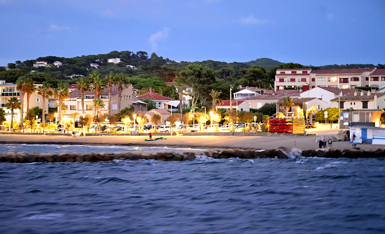 Le front de mer illuminé à la tombée de la nuit, vu depuis la mer