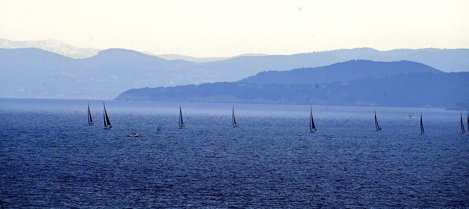 Une régate sur la mer, collines bleues à l'horizon